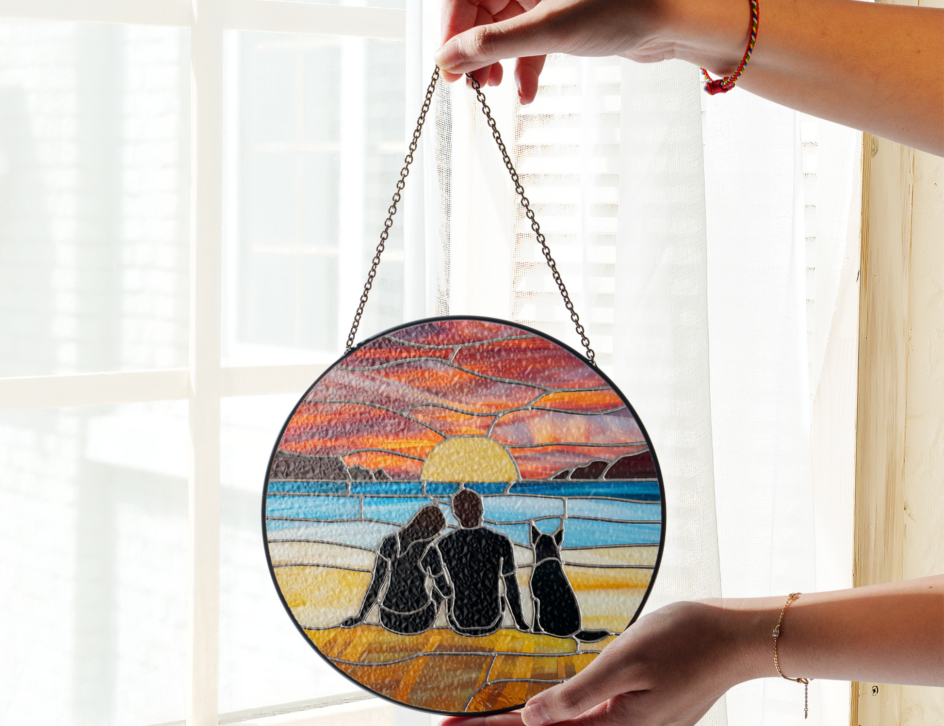 couple and dog at beach at sunset suncatcher in front of window