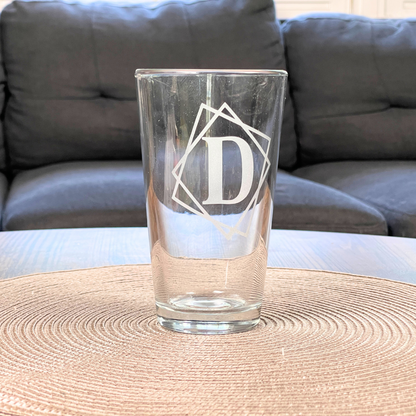 personalized pint glass with framed initial on a table