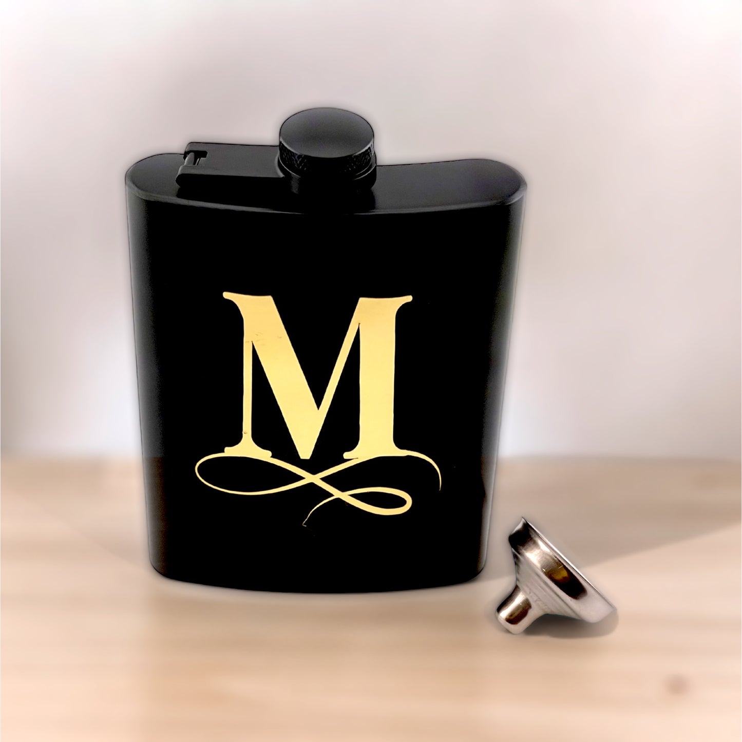 initial with flourish on black flask with funnel