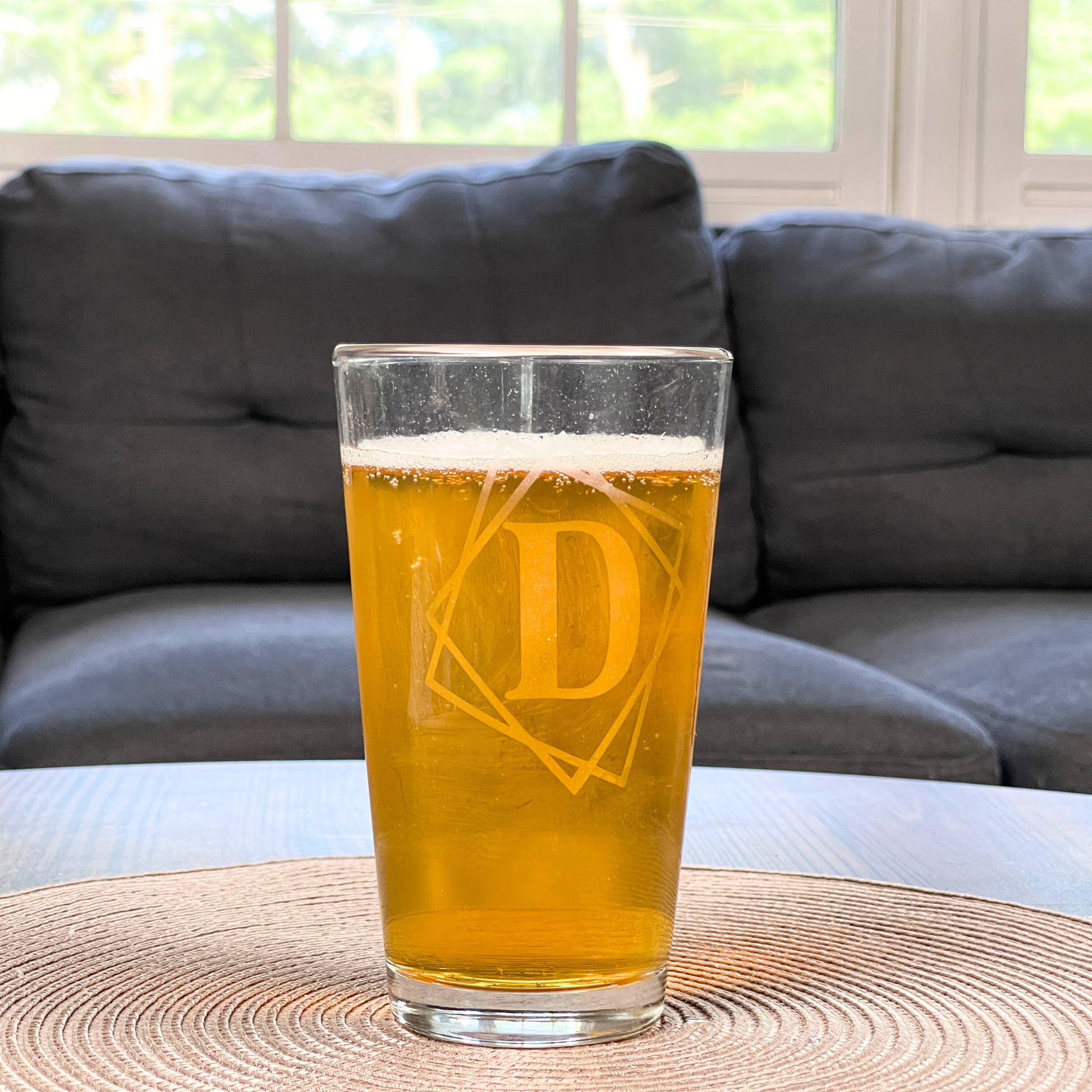 personalized pint glass with framed initial on a table filled with beer