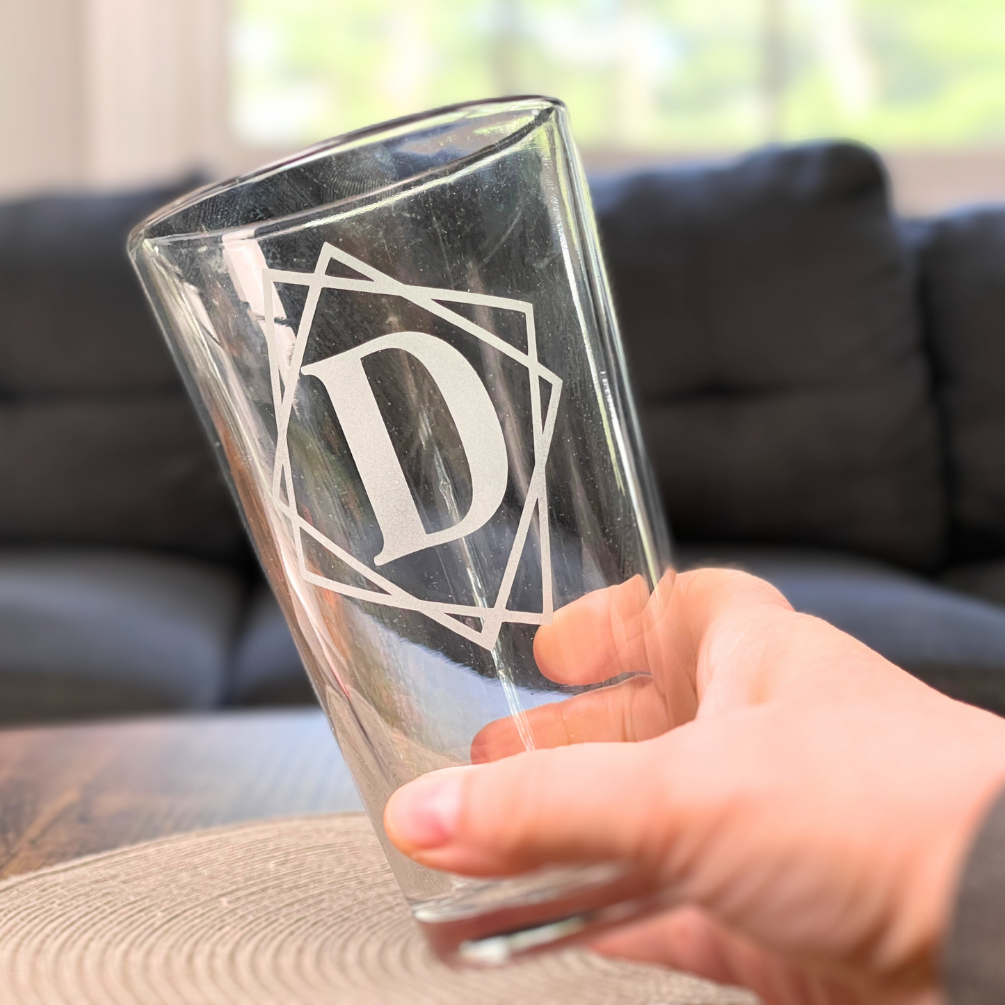 hand holding empty personalized pint glass with framed initial