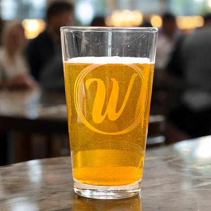 personalized pint glass with initial in a circles in a bar