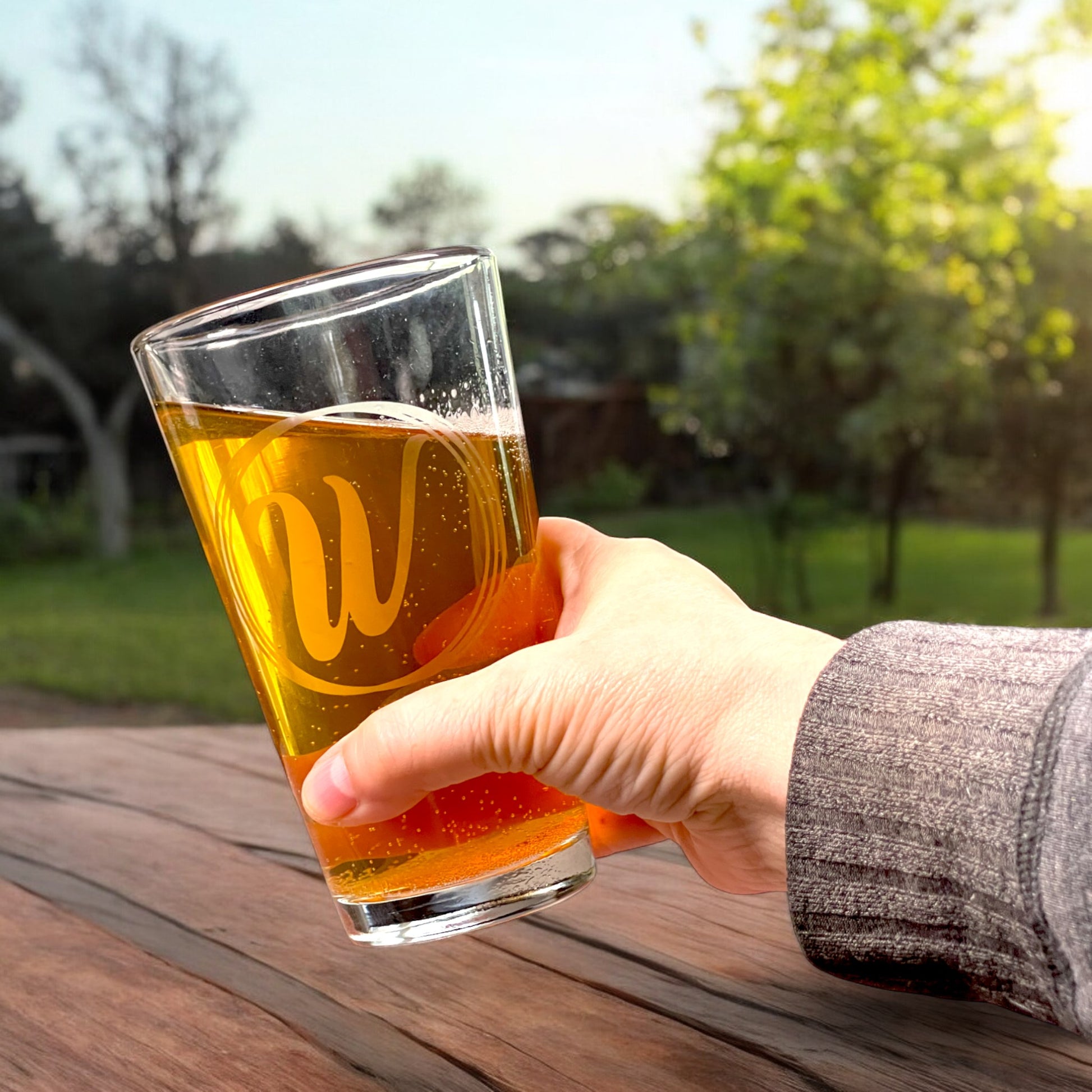 personalized pint glass with initial in a circles held in hand