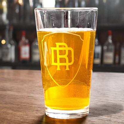 personalized pint glass with shield and monogram on a bar